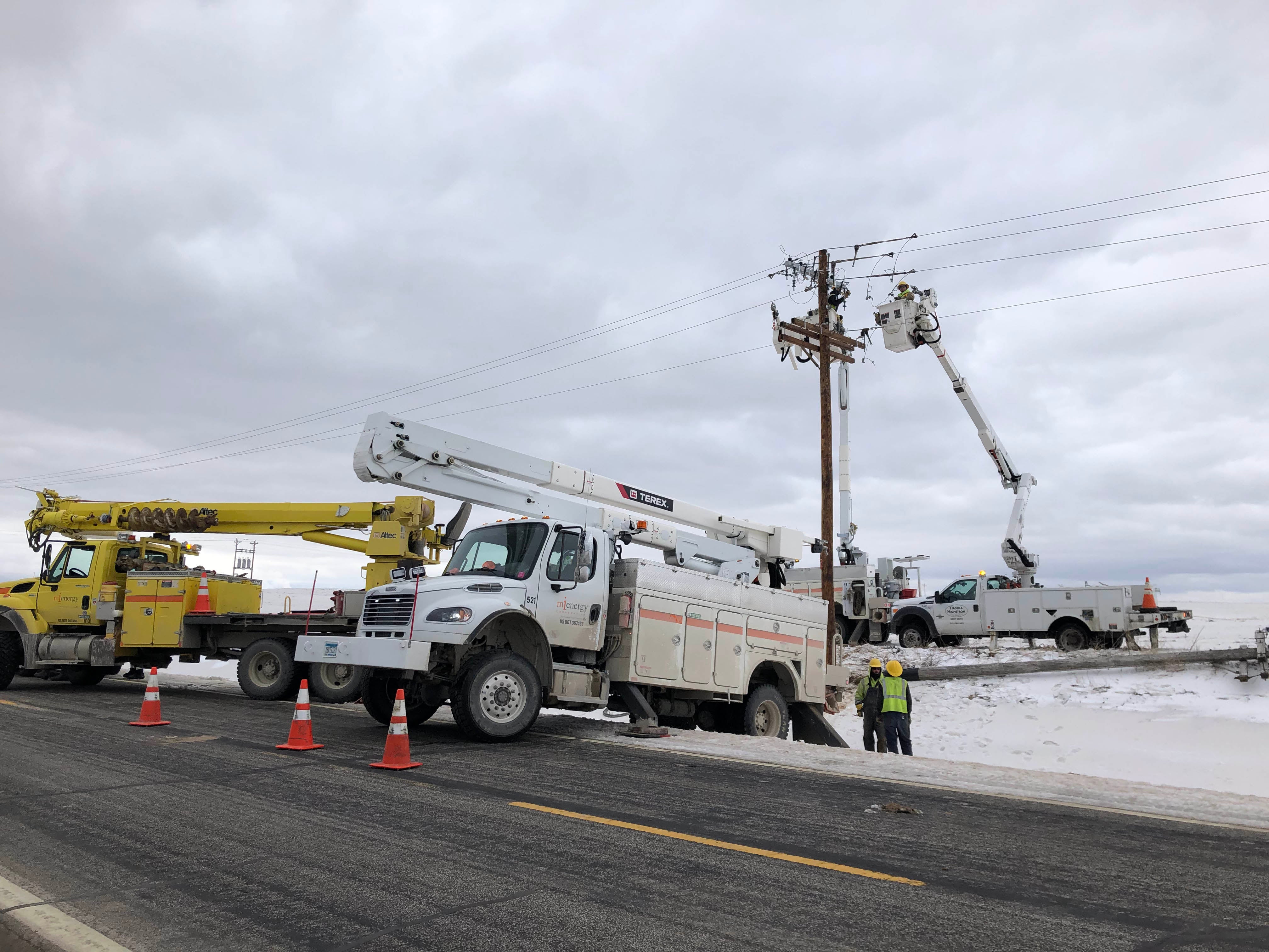 photo showing two bucket trucks fixing power line